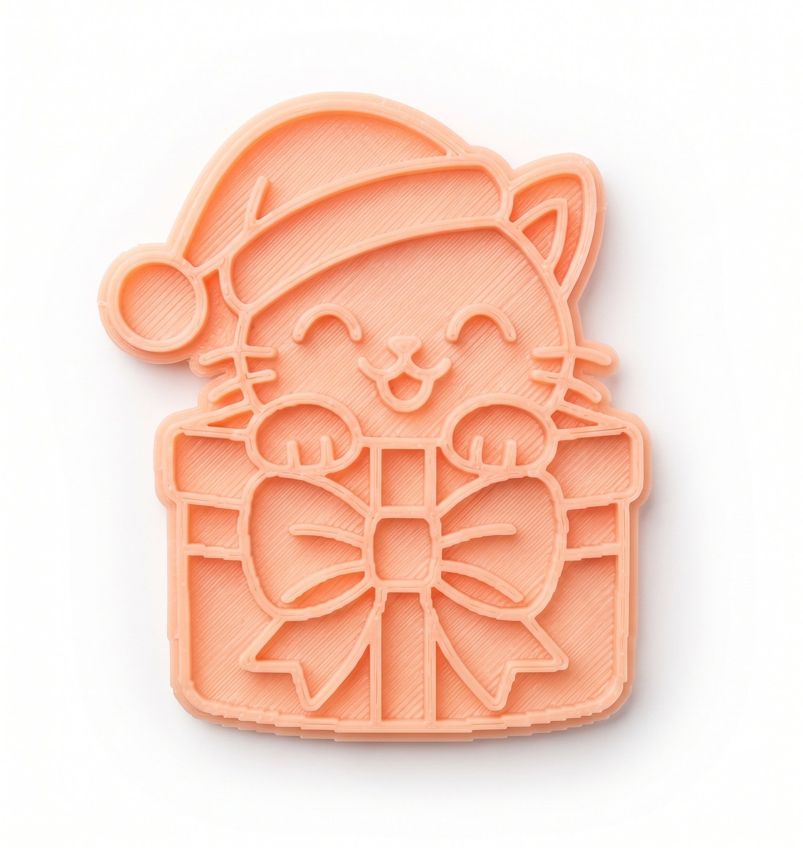 Cortador e marcador de biscoito na cor pêssego com formato de gatinho de Natal em uma caixa de presente.