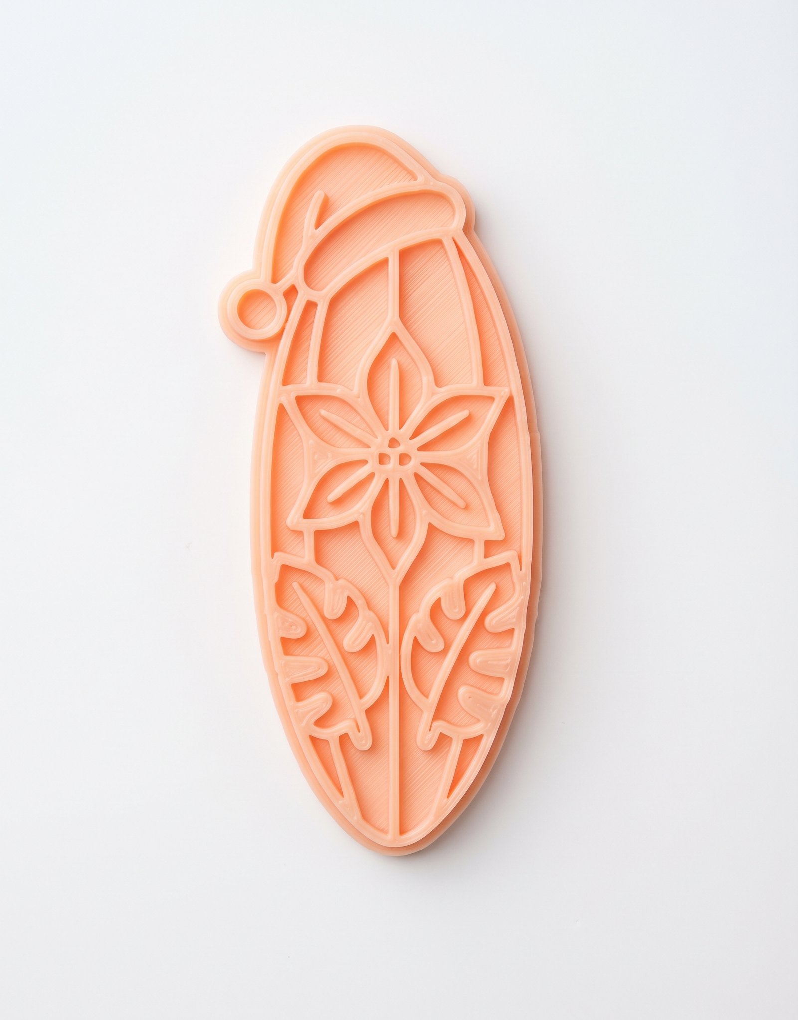 Cortador e marcador de biscoito na cor rosa salmão em formato de prancha de surf natalina.