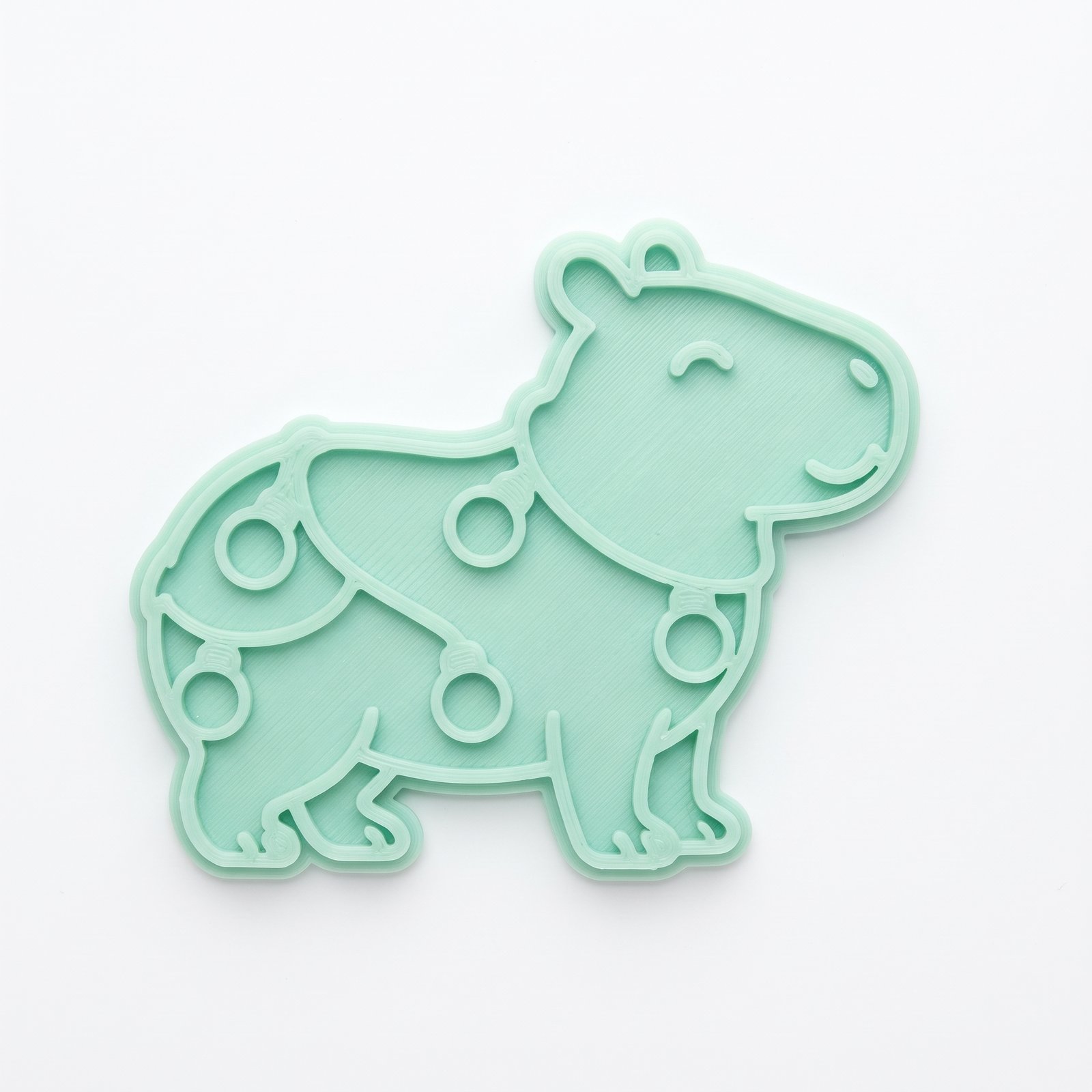 Cortador e marcador verde em formato de capivara decorada com luzes de Natal.