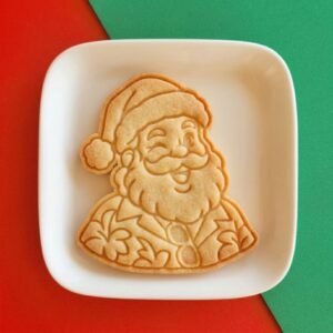 Biscoito assado e decorado em formato de Papai Noel tropical piscando com camisa florida sobre prato branco