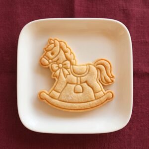 Biscoito assado no formato de cavalo de balanço decorado em prato branco