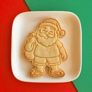 Biscoito assado com a marcação do Papai Noel tropical usando camiseta, bermuda, chinelos e gorro de Natal em um pratinho branco.