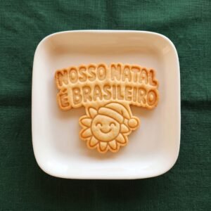 Biscoito pronto em um prato branco com a frase gravada Nosso Natal é Brasileiro e um sol com gorro de Papai Noel